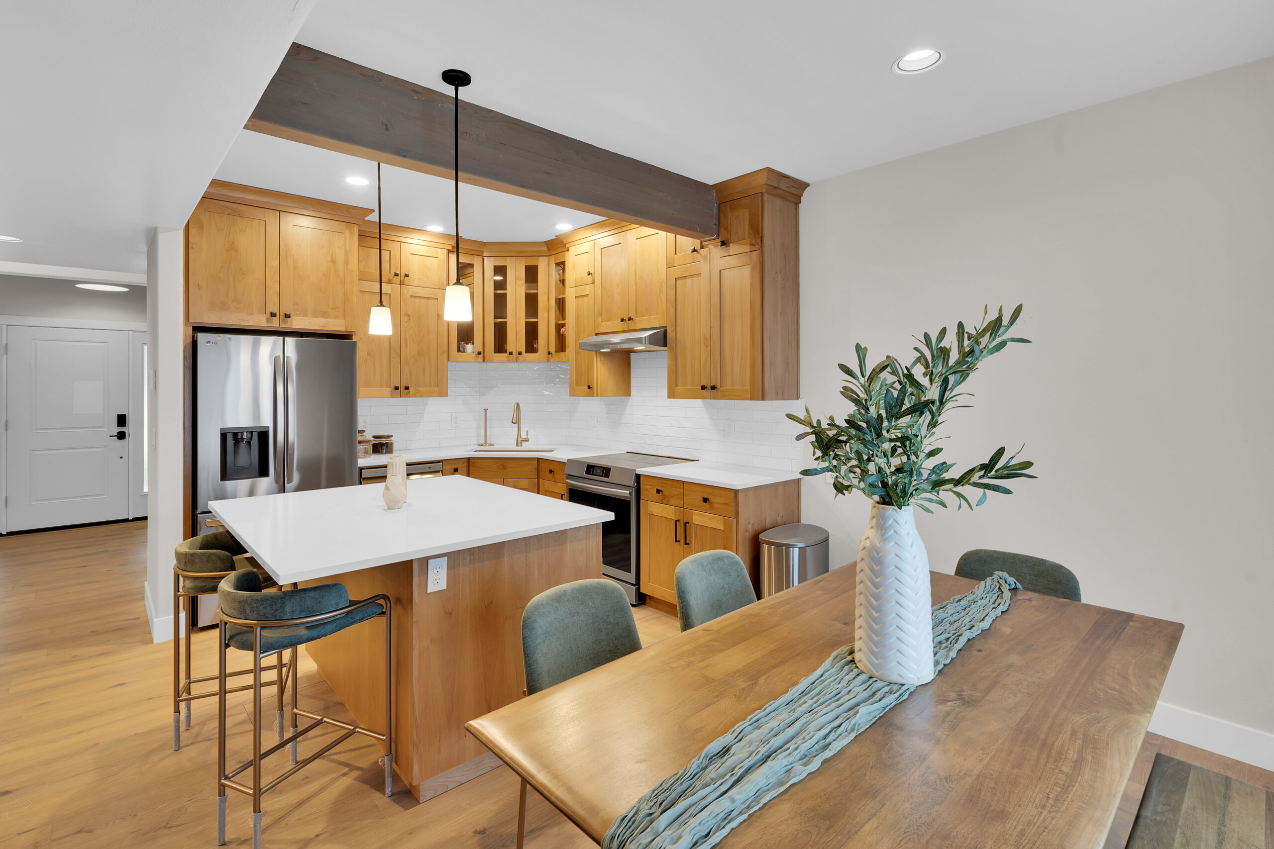 Spacious modern kitchen featuring white cabinets, marble countertops, and an island with stainless steel fixtures.