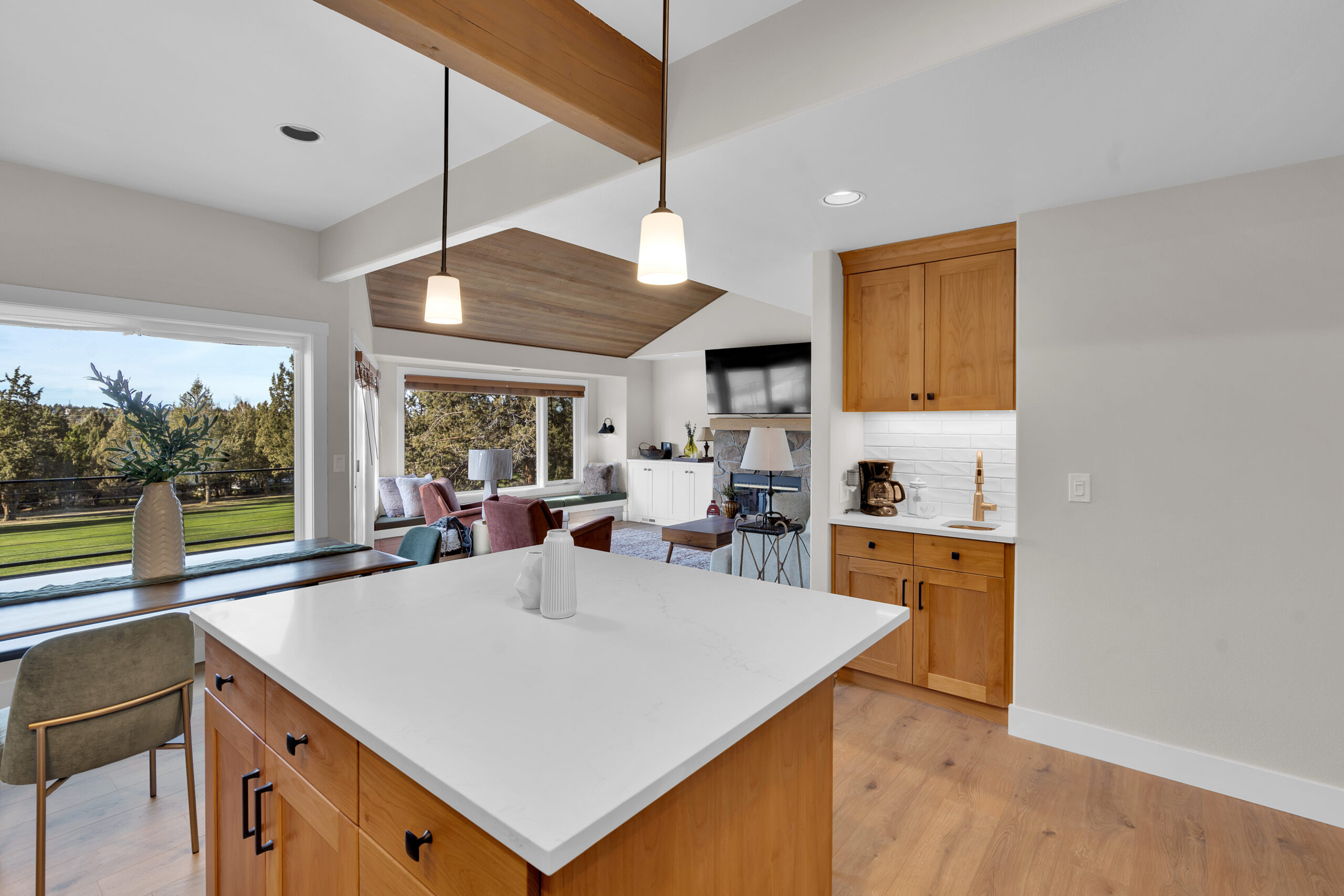 Spacious modern kitchen featuring white cabinets, marble countertops, and an island with stainless steel fixtures.