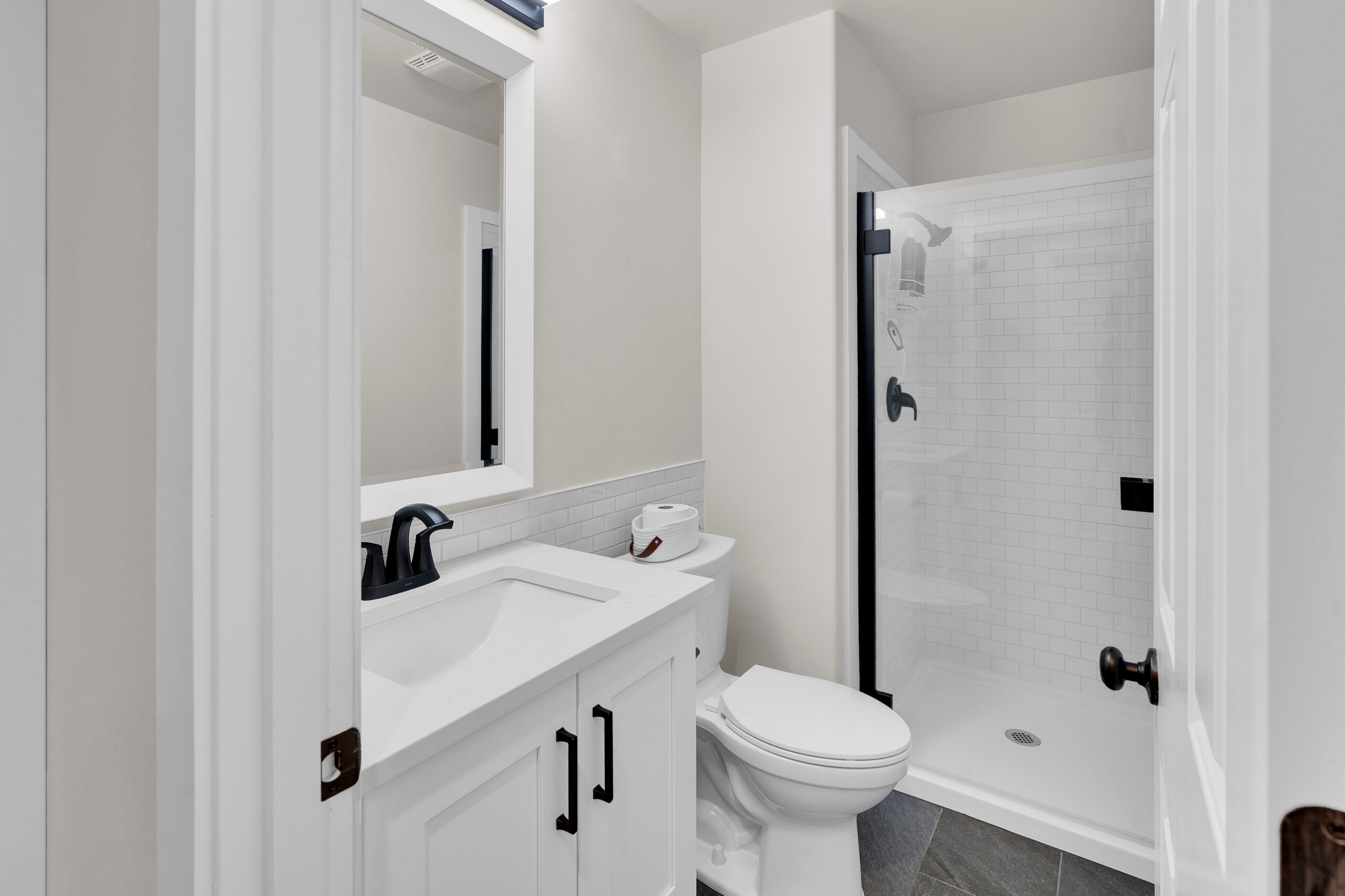 Elegant white bathroom with glass shower and stylish patterned floor.