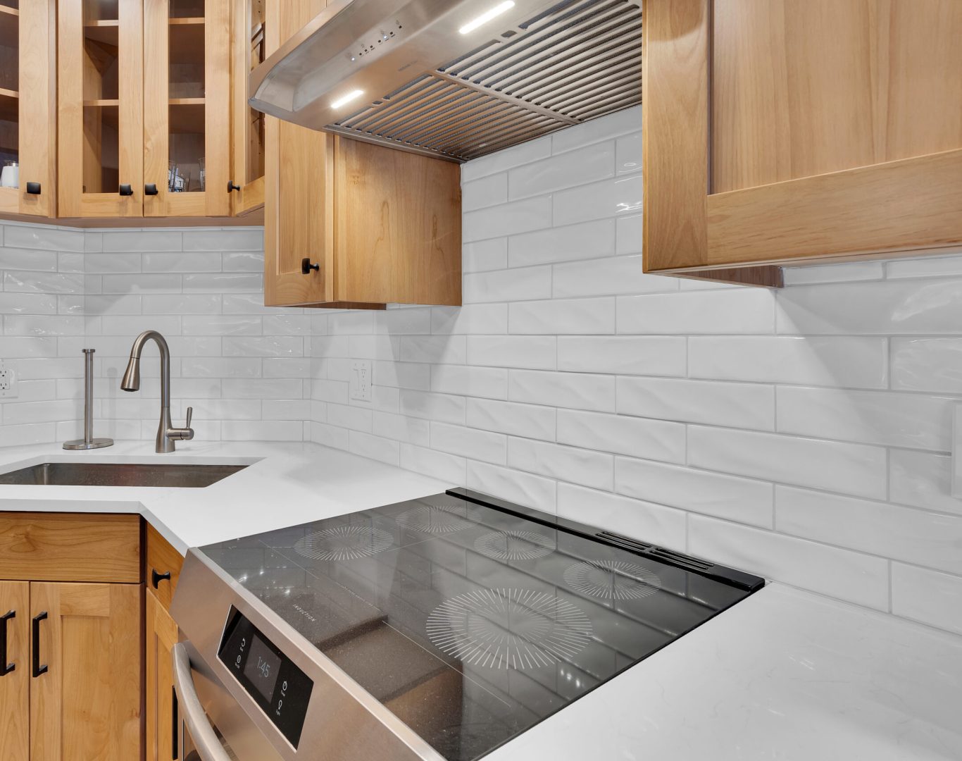 Spacious modern kitchen featuring white cabinets, marble countertops, and an island with stainless steel fixtures.