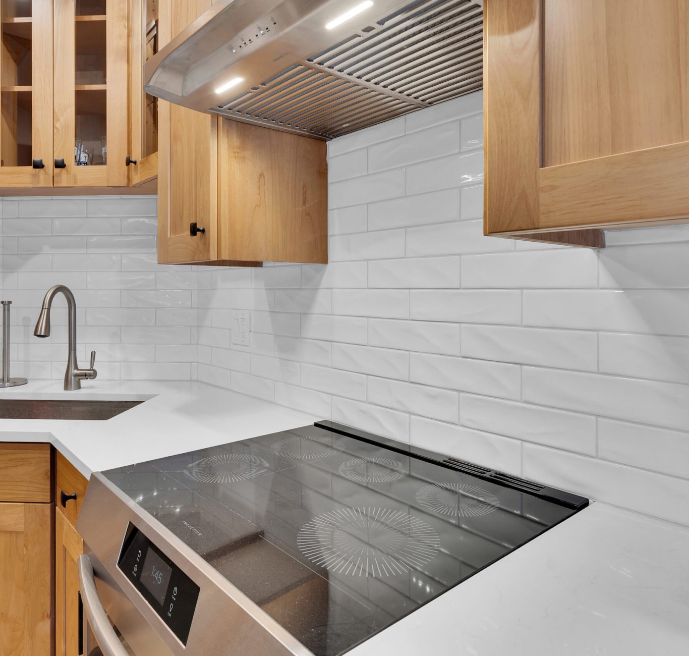 Spacious modern kitchen featuring white cabinets, marble countertops, and an island with stainless steel fixtures.