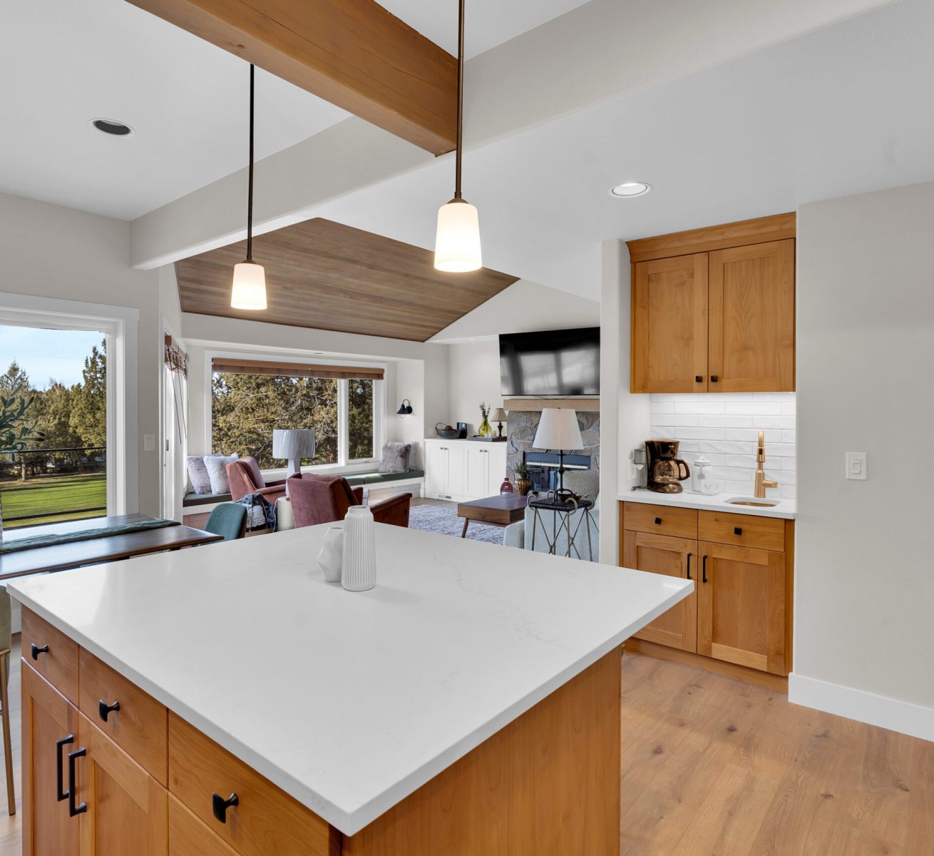 Spacious modern kitchen featuring white cabinets, marble countertops, and an island with stainless steel fixtures.